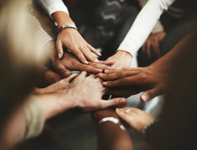 Diverse group of people stacking their hands together in a gesture of teamwork and unity.