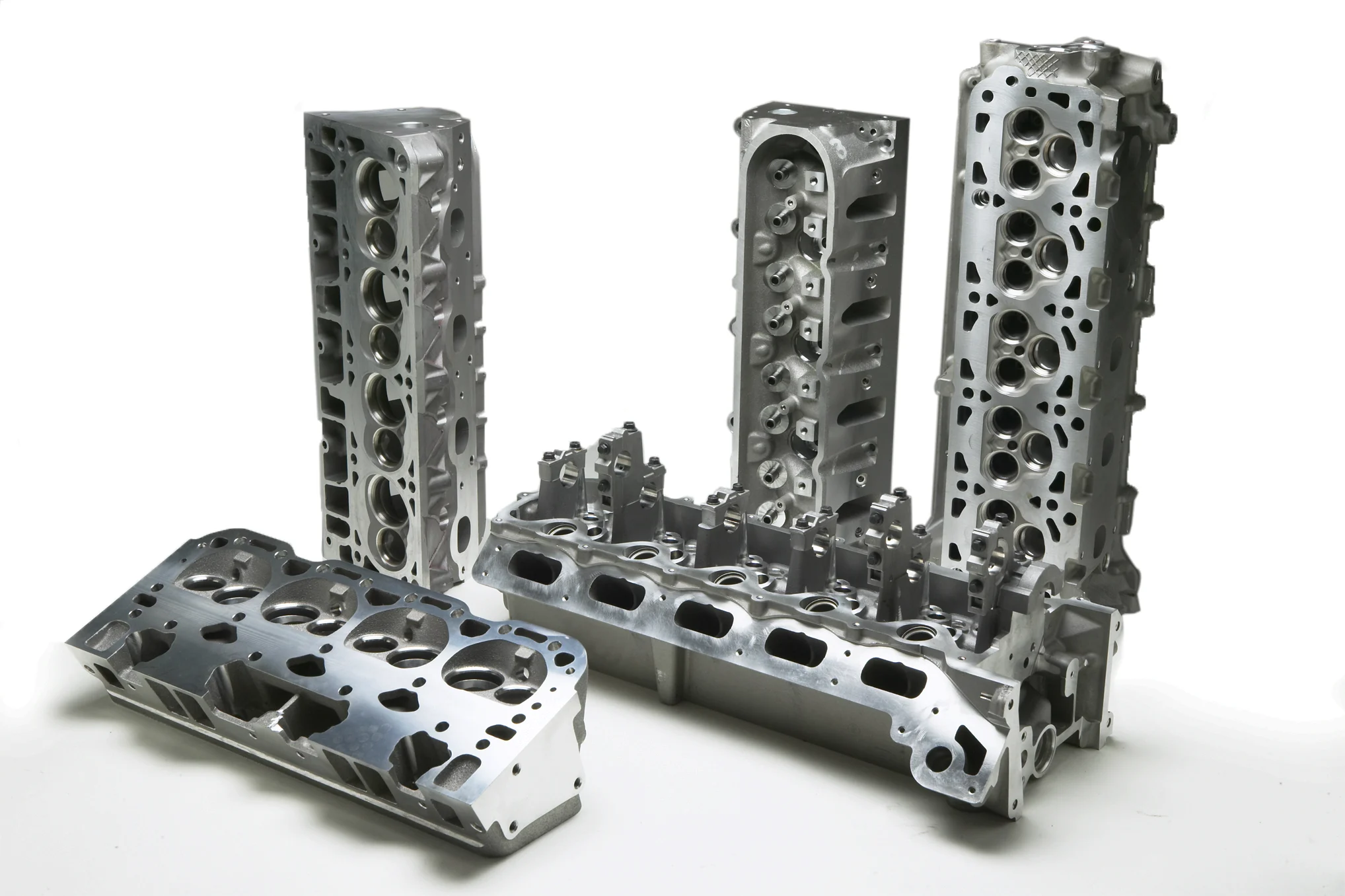 Cast aluminum engine cylinder heads arranged on a white background, showcasing intake and exhaust ports.