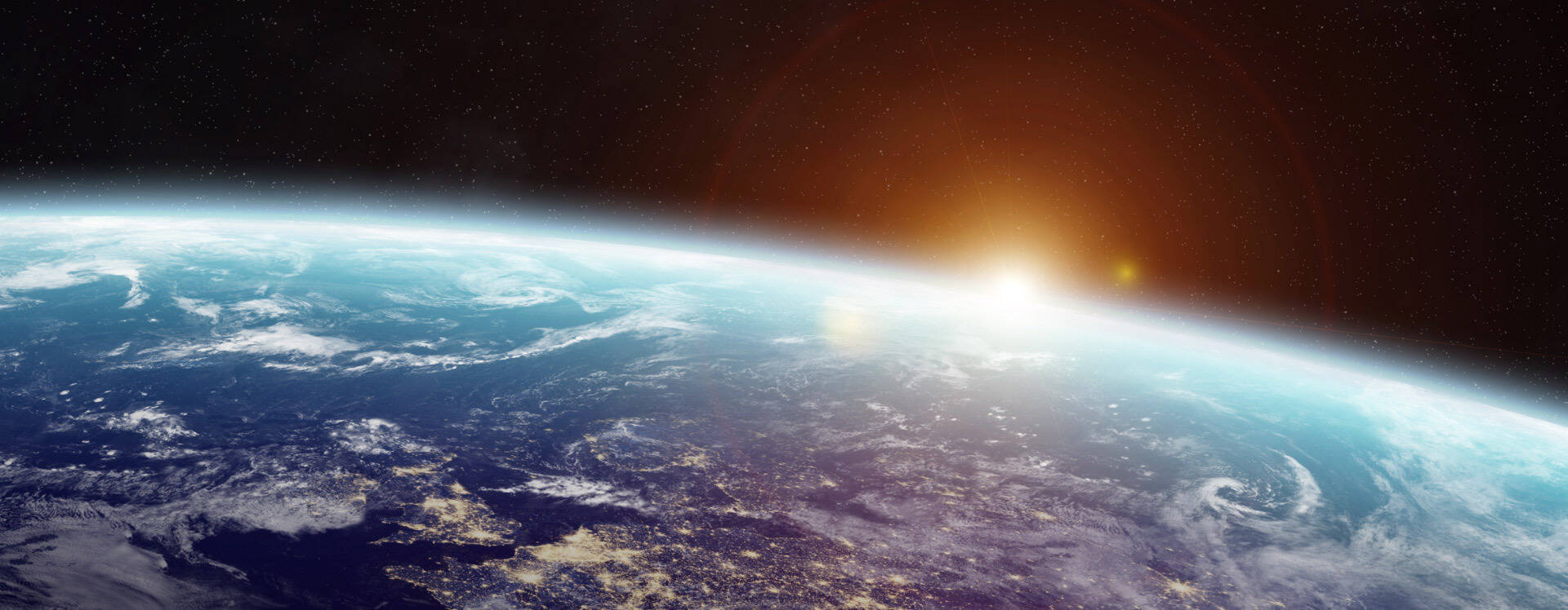 View of Earth’s horizon from space with the sun rising above the atmosphere, highlighting the planet’s curvature and cloud formations.
