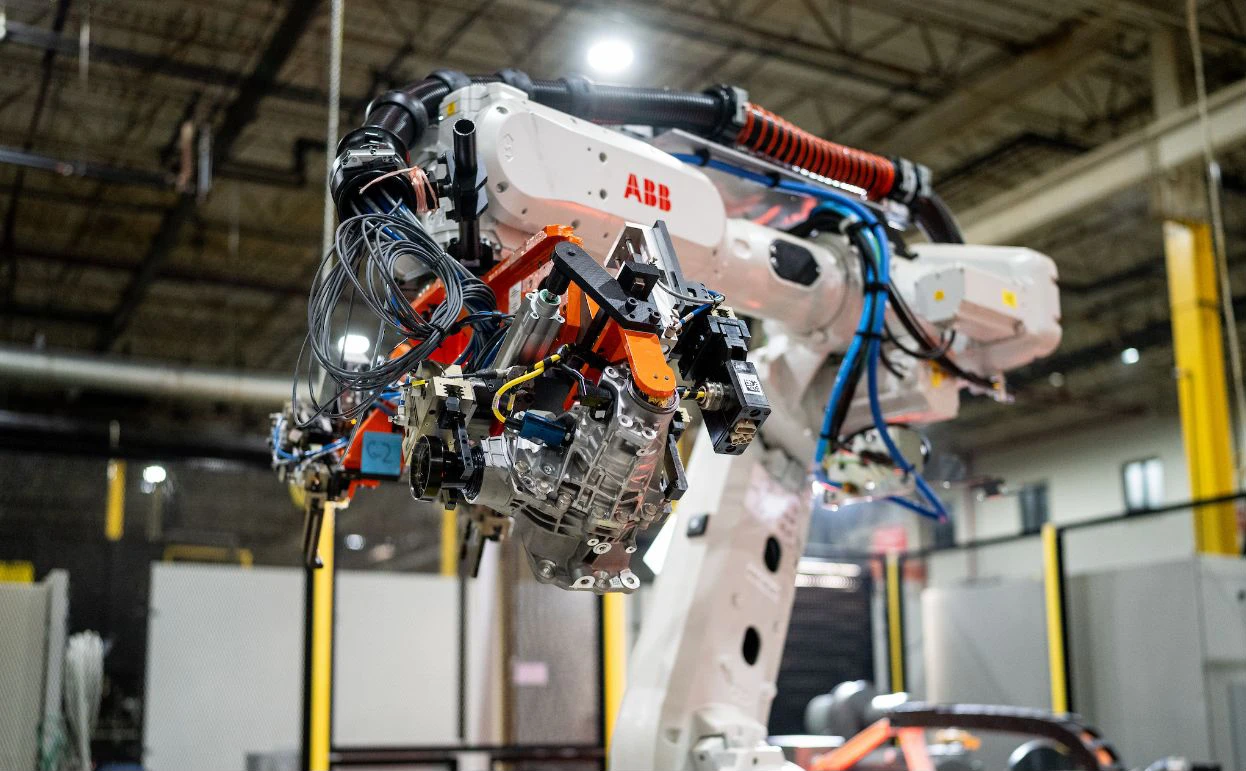 Close-up of an industrial robotic arm equipped with advanced sensors and tools inside a modern manufacturing facility.
