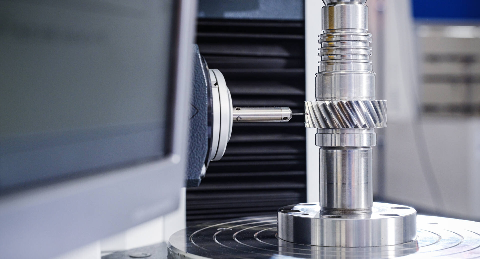 Close-up of a precision measurement device inspecting a metallic cylindrical gear component in a laboratory setting.