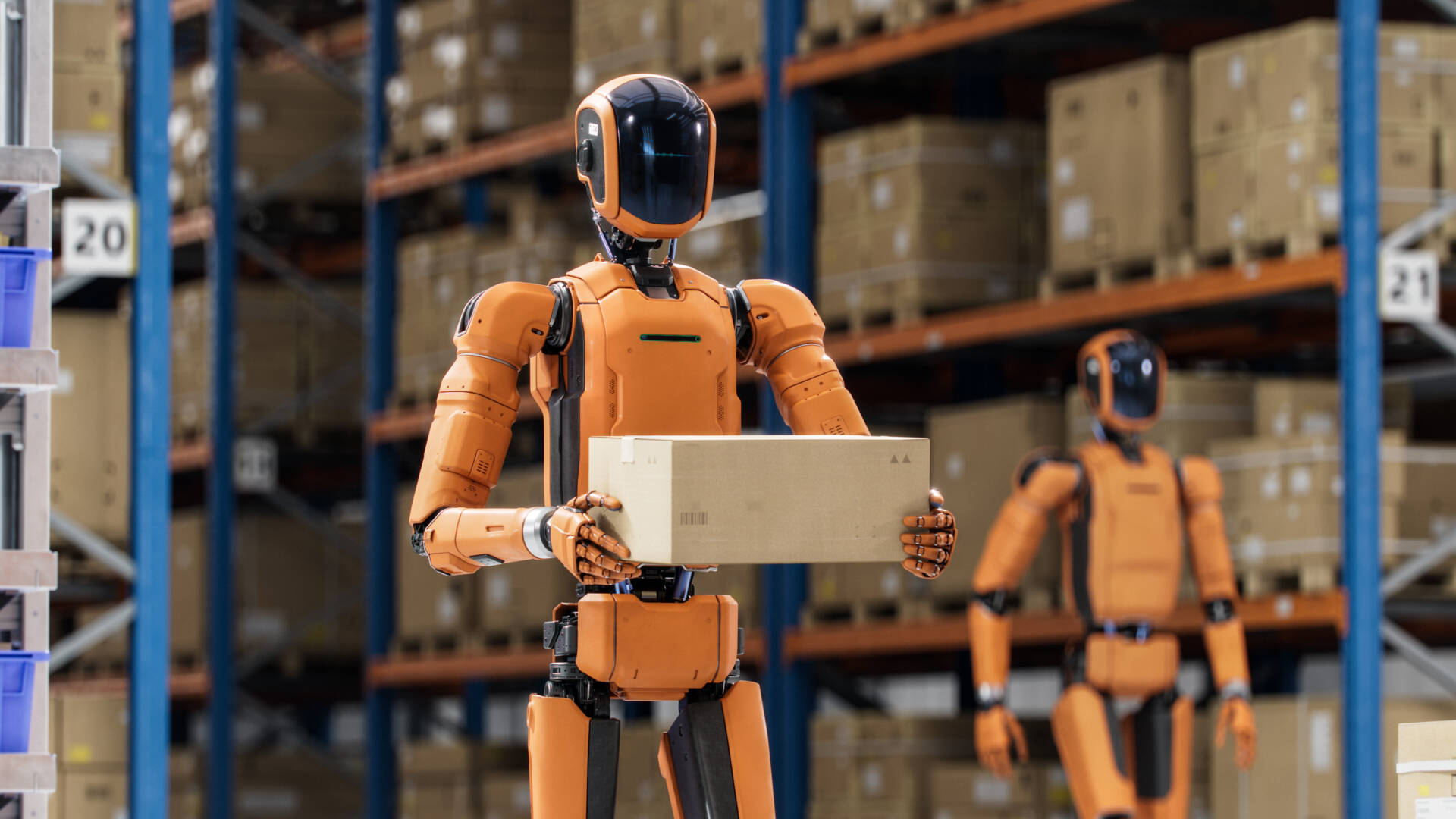 Orange humanoid robots handling cardboard boxes in a warehouse with shelves stacked with inventory.