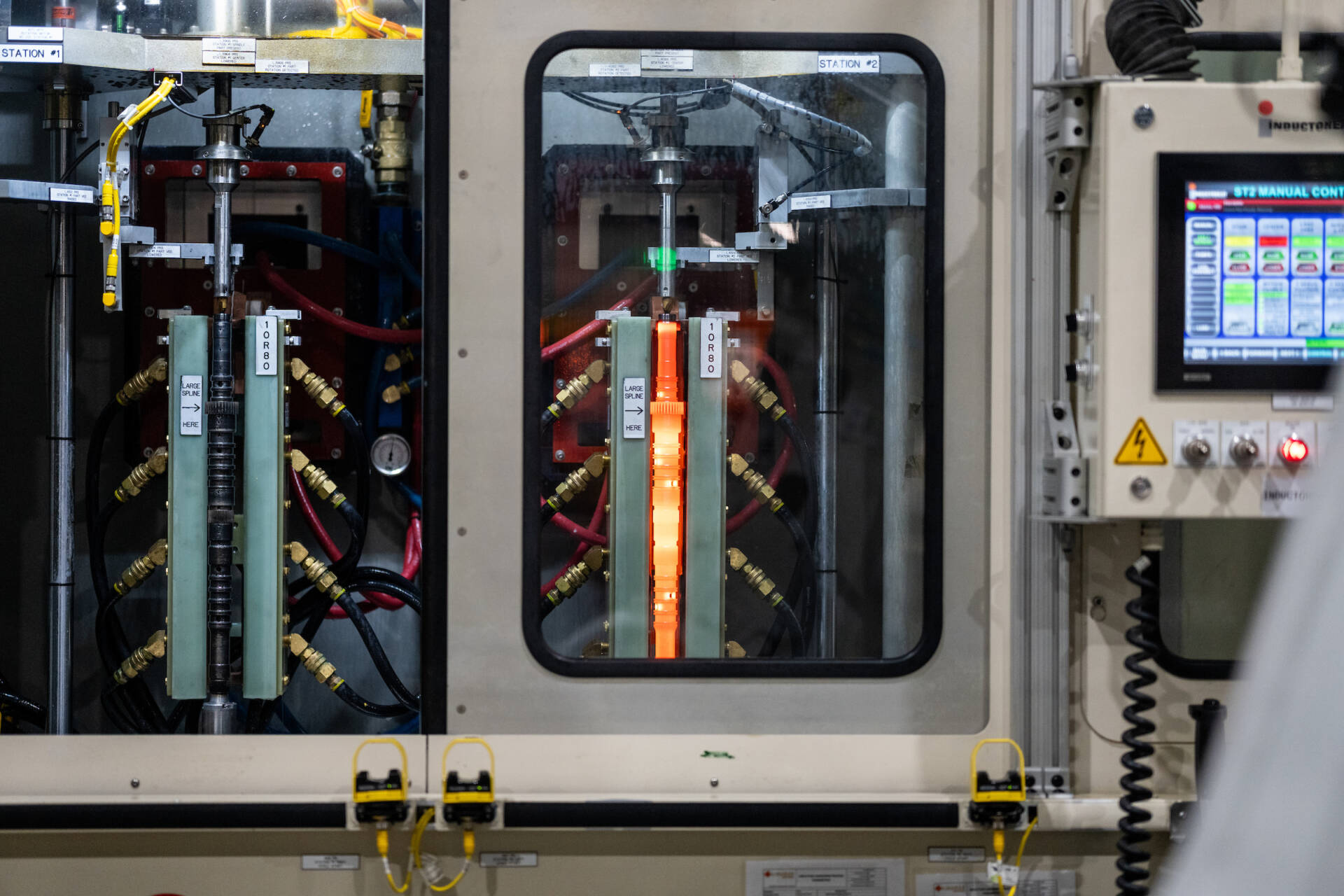 Close-up of an industrial machine with electronic components and a touchscreen control panel in a manufacturing setting.