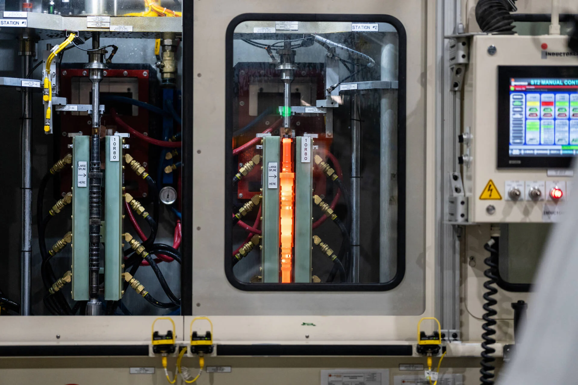 Close-up of an industrial machine with electronic components and a touchscreen control panel in a manufacturing setting.