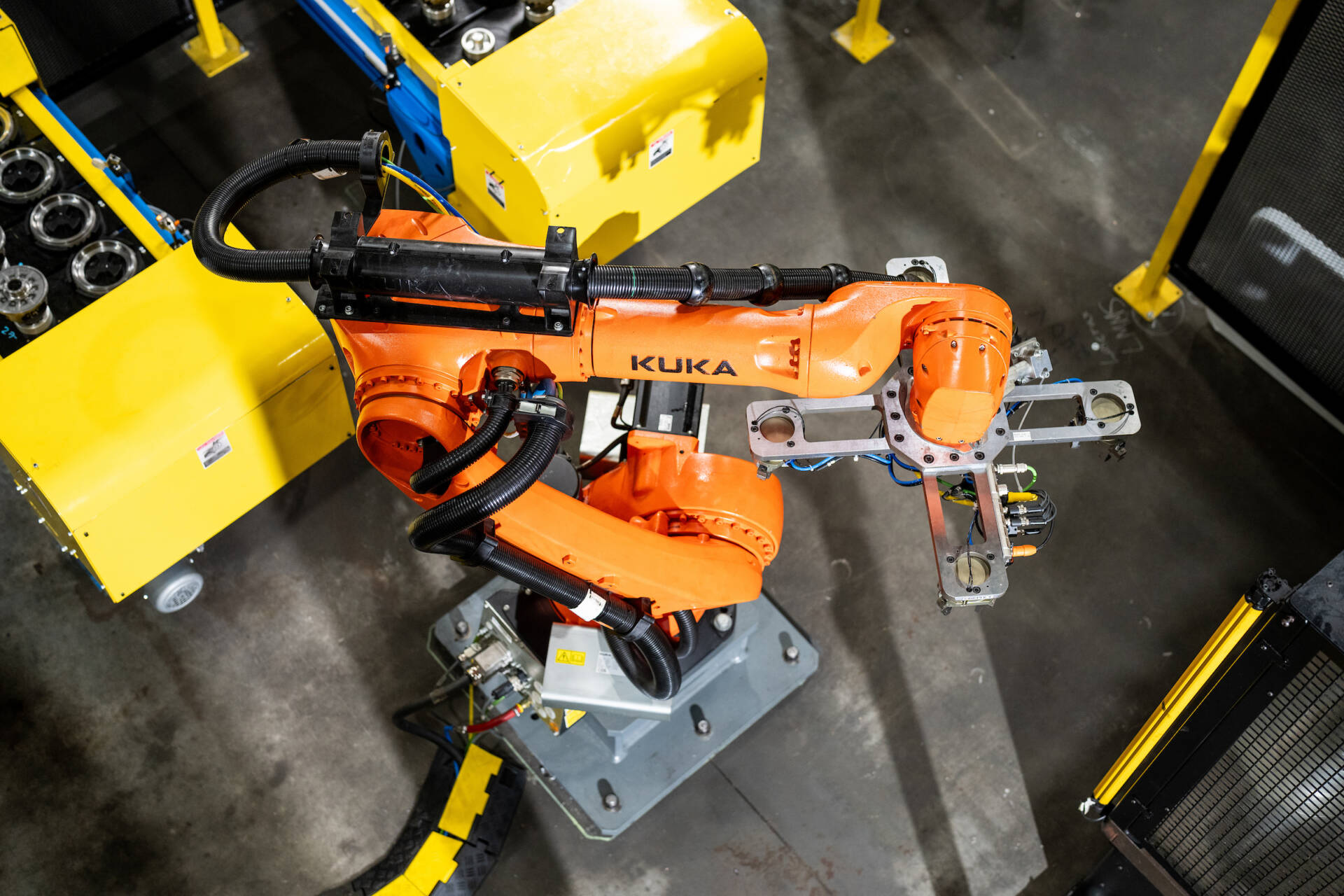 Industrial orange robotic arm operating in a high-tech manufacturing facility.