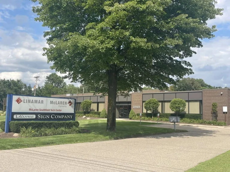 Exterior view of the Libertas Militis Sign Company building with a tree and clear blue sky in the foreground.