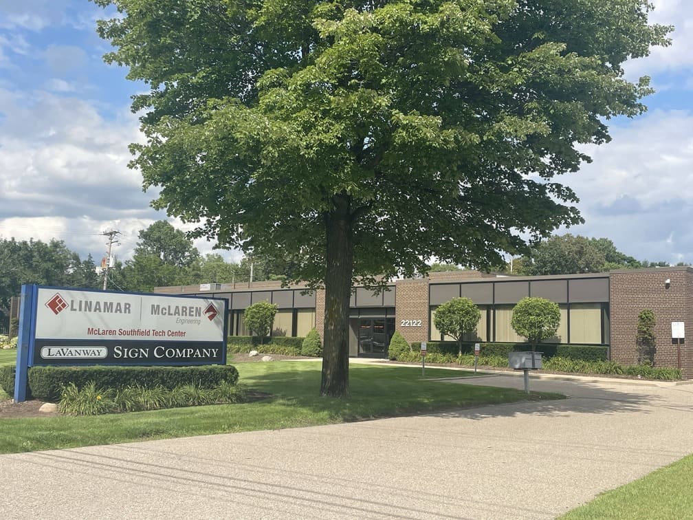 Exterior view of the Libertas Militis Sign Company building with a tree and clear blue sky in the foreground.