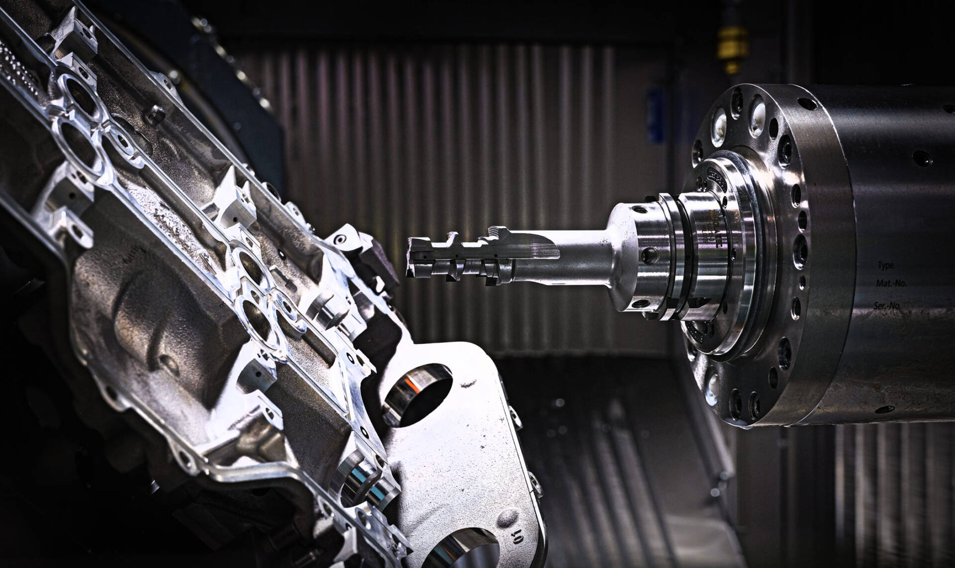 Close-up of a CNC machine tool precisely milling a complex metal automotive part inside an industrial workshop.
