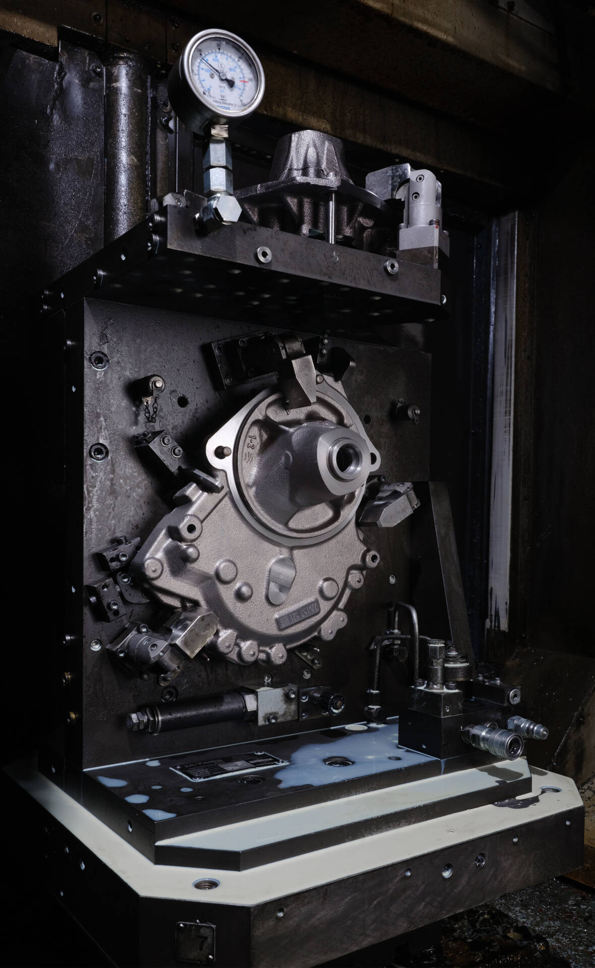 Close-up of an industrial machine component with pressure gauges and metal fittings inside a manufacturing setup.