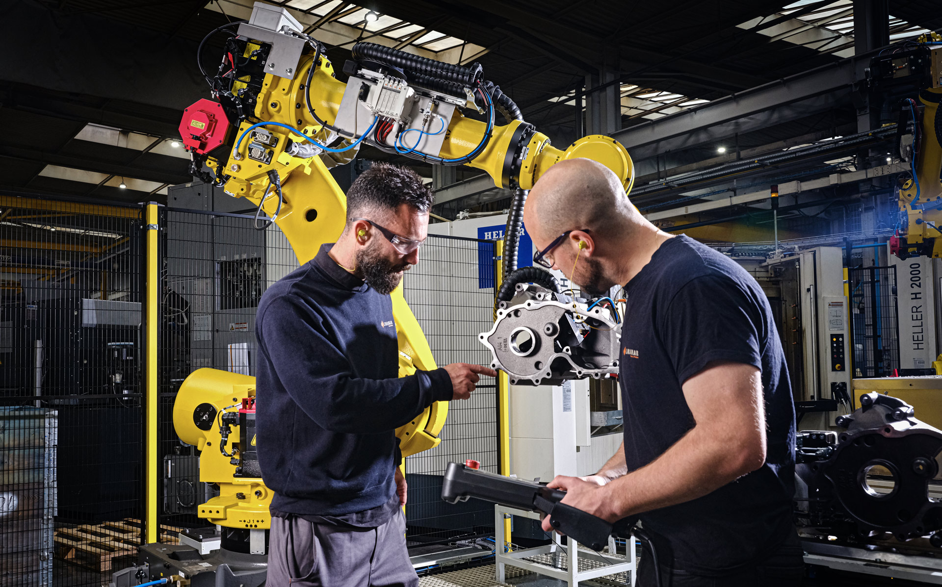 Two engineers inspecting a robotic arm component in a modern industrial automation facility.