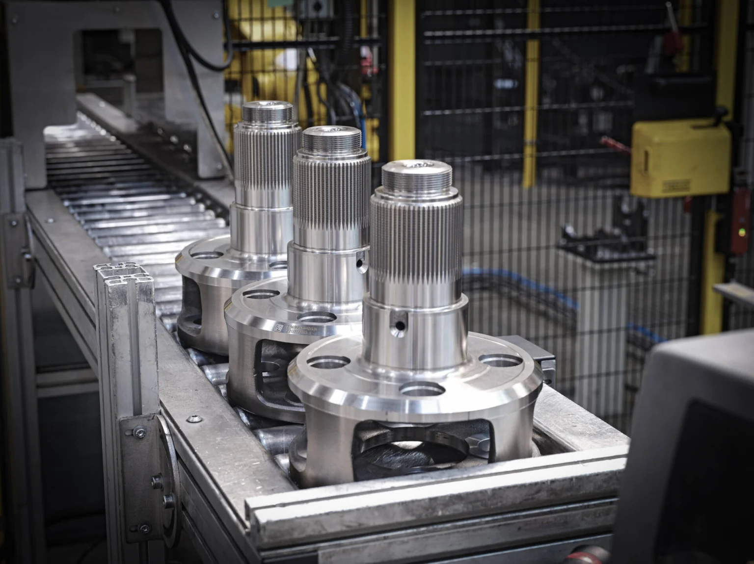 Close-up of precision metal components arranged on a conveyor belt in an industrial manufacturing facility.