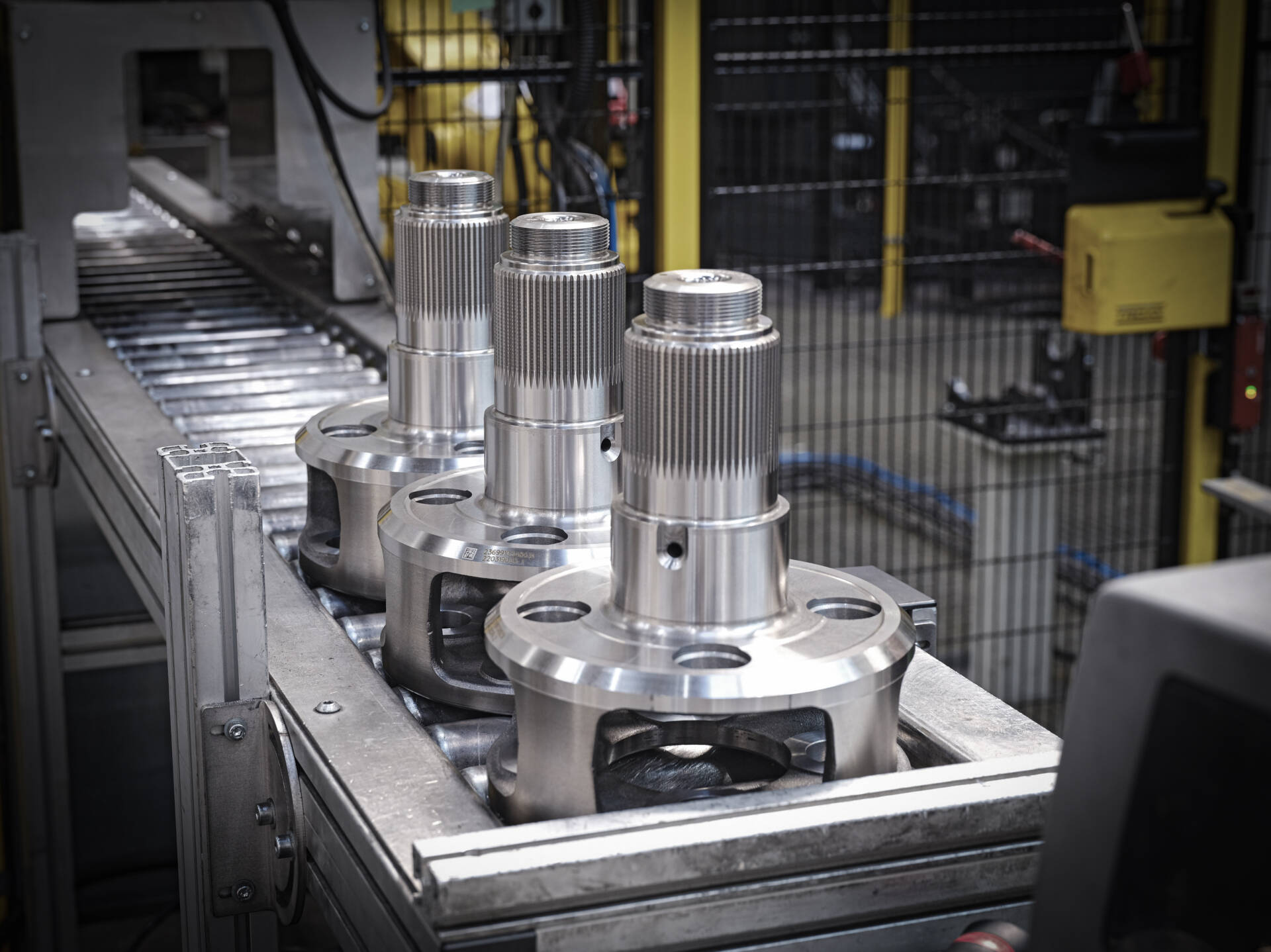Close-up of precision metal components arranged on a conveyor belt in an industrial manufacturing facility.