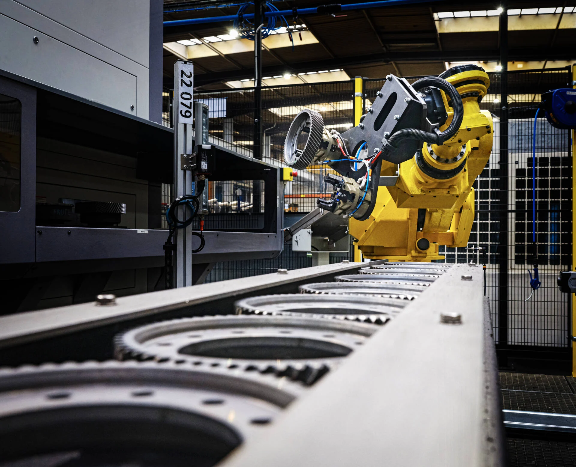 Industrial robotic arm assembling or inspecting mechanical parts on a conveyor belt inside a manufacturing facility.