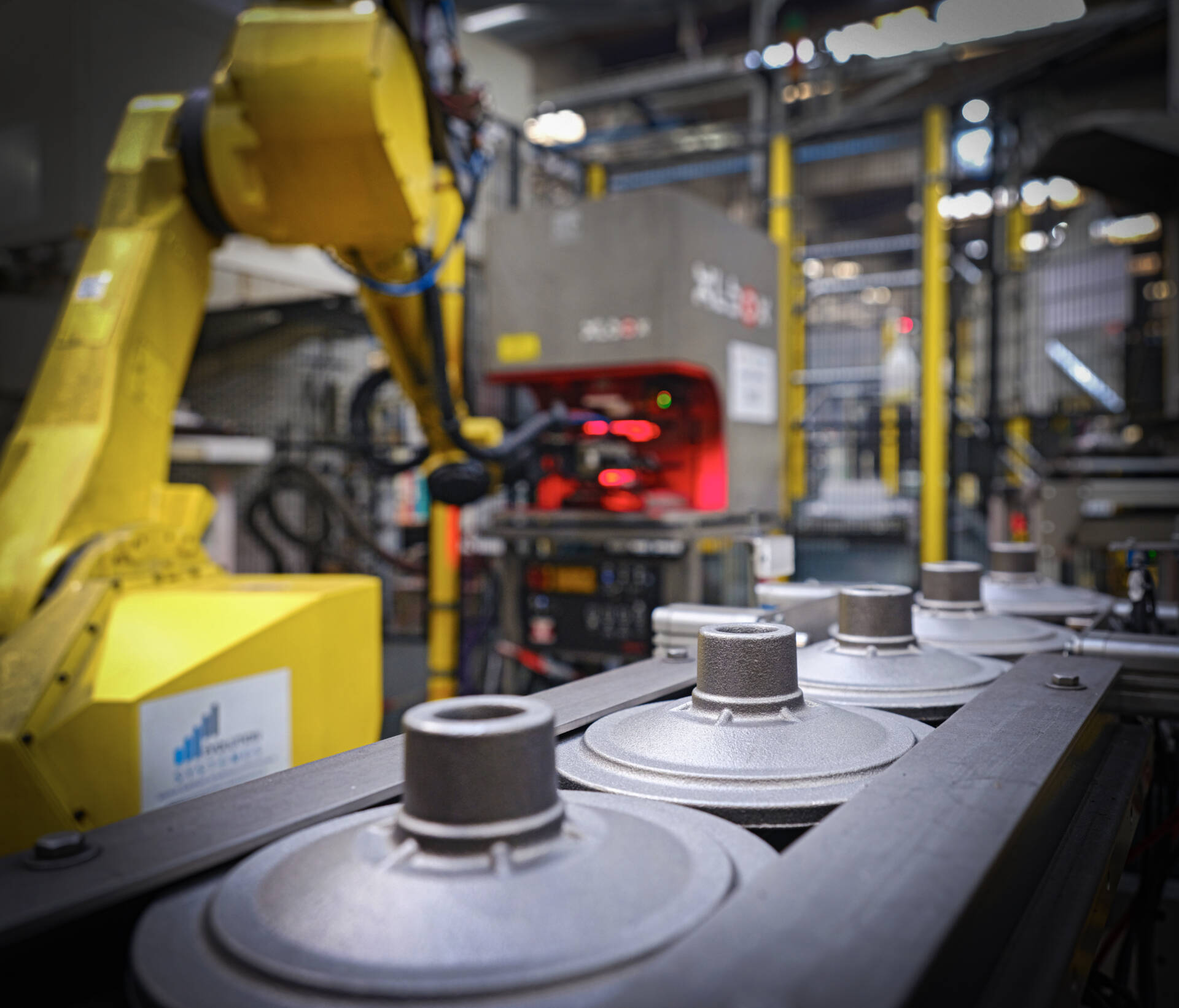 Industrial robotic arm operating on an assembly line producing metal parts in a factory setting.