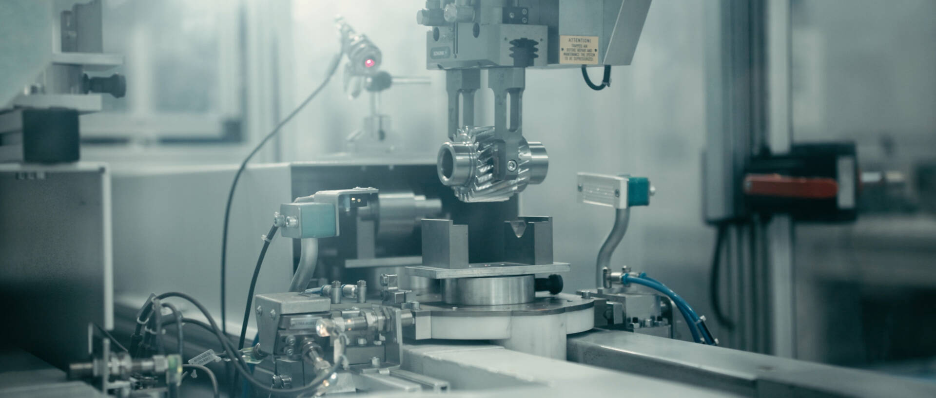 Close-up of a precision machine operating in an industrial manufacturing setting with various metal components and control mechanisms.