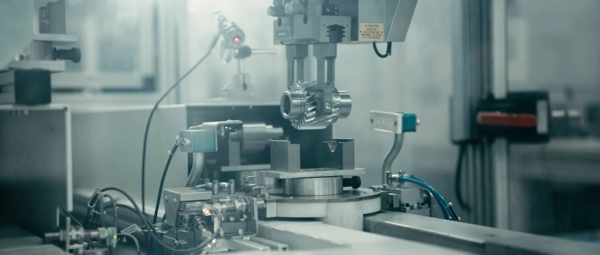 Close-up of a precision machine operating in an industrial manufacturing setting with various metal components and control mechanisms.