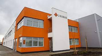 Modern two-story commercial building with orange and white exterior walls under a cloudy sky.