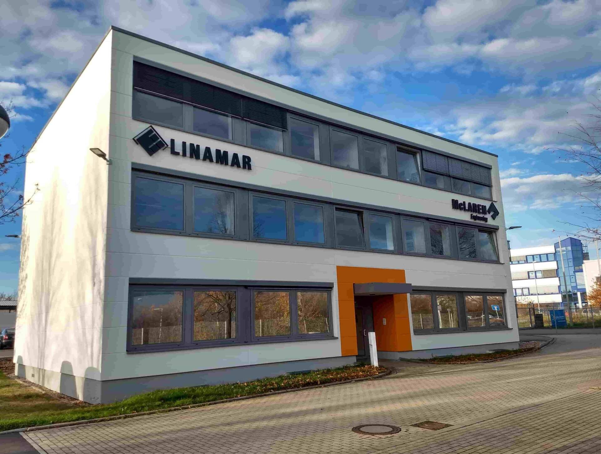 Modern three-story office building with Linamar branding under a partly cloudy sky.